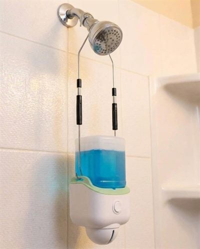 An automatic shower cleaner hanging from a shower head, its reservoir filled with blue daily cleaner.